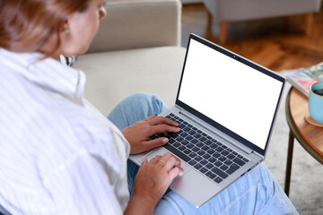 Cropped image of woman using laptop with blank white screen at home