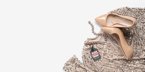 Stylish female dress, shoes, bracelet and sale tag on white background with space for text. Black Friday
