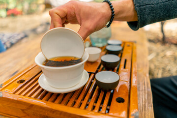 Close-up shot of natural Chinese tea leaves being brewed in a special ceramic bowl with lid during...