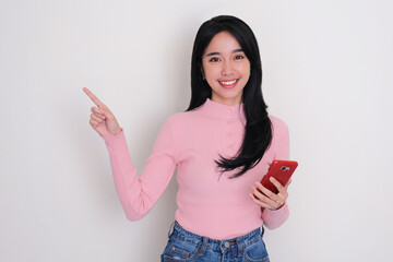 A woman smiling and holding phone with one hand pointing to the right side