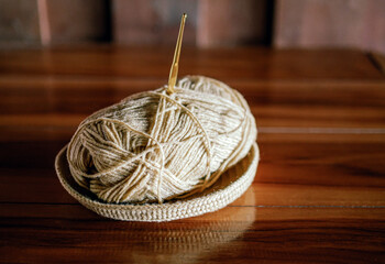 A yarn with a knitting needle stuck in it lies on a wooden table, Hobby crafts with yarn, hand made.