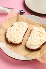 Plate of tasty sandwiches with cream cheese on pink background