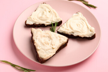 Plate of tasty sandwiches with cream cheese on pink background