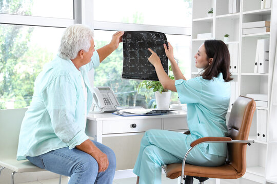 Female doctor showing x-ray scan to senior patient in medical office