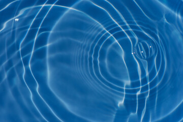 Defocus blurred transparent blue colored clear calm water surface texture with splashes reflection. Trendy abstract nature background. Water waves in sunlight with copy space. Blue watercolor shine.