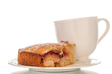 Sweet homemade pie with plums on a white ceramic saucer with a cup, macro, isolated on white background.