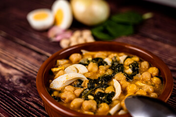 Delicious and traditional dish of chickpea stew with spinach and egg - obrazy, fototapety, plakaty