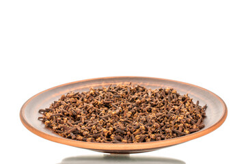 Dry aromatic cloves in a clay dish, macro, isolated on a white background.