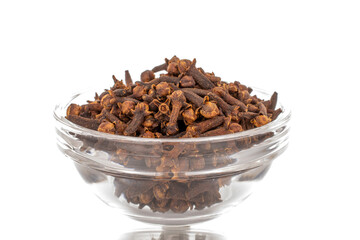 Dry aromatic cloves in a glass bowl, macro, isolated on white background.