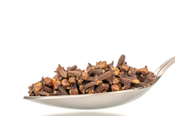 Dry aromatic cloves in a metal spoon, macro, isolated on a white background.