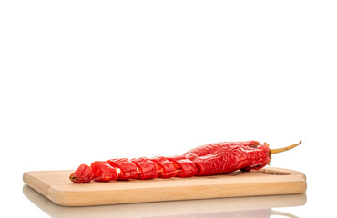 One red hot pepper cut into pieces on a wooden kitchen board, macro, isolated on white background.