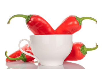 Several sweet red peppers with white ceramic cup, macro, isolated on white background.