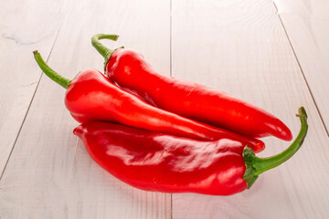 Three sweet red peppers on a wooden table, macro.