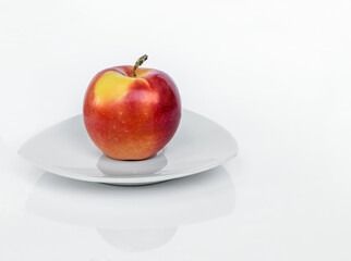 Ripe Gala apple on a porcelain plate isolated on a white