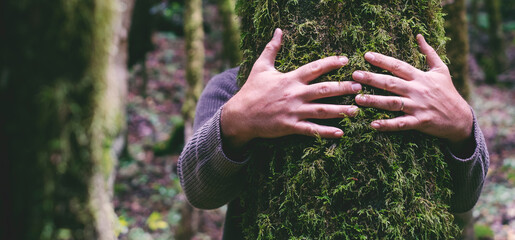 Love for nature concept with man hands hugging bonding green musk trunk tree in the forest woods. Environment and protection. Lover planet. People in outdoor leisure activity alone. Embracing trees - obrazy, fototapety, plakaty