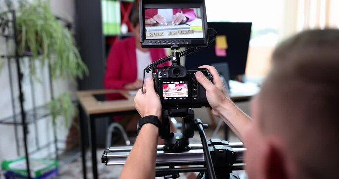 A man operator takes a woman in the office on a digital camera, back view. Data science, slowmotion