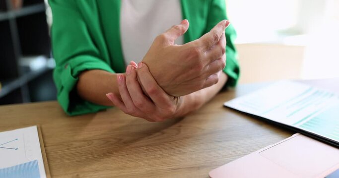 The pain in the hand of a woman in the office, closeup, slowmotion. Carpal tunnel syndrome, the health of a woman
