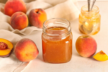 Jar with sweet peach jam and fresh fruits on light background