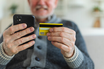 Senior man shopping online holding smartphone paying with credit card. Old grandfather buying on Internet enter credit card details. Online shopping delivery service Older generation modern tech usage