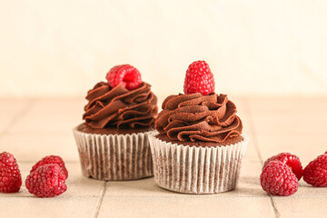 Tasty chocolate cupcakes with raspberries on table