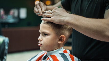 The master hairdresser works with a hair clipper and cuts the boys. Medium frame view, hand held...
