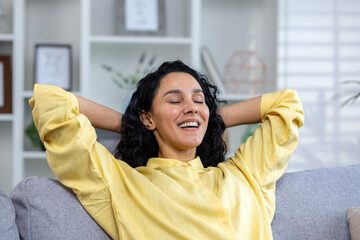 Close up of successful smiling and satisfied woman with hands behind head with closed eyes smiling...