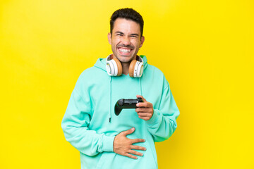 Young handsome man playing with a video game controller over isolated wall smiling a lot