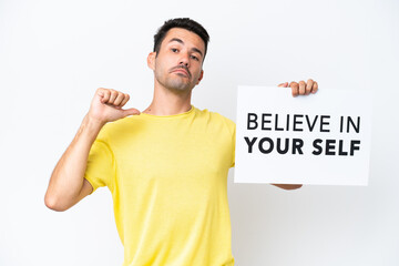 Young handsome man over isolated white background holding a placard with text Believe In Your Self with proud gesture