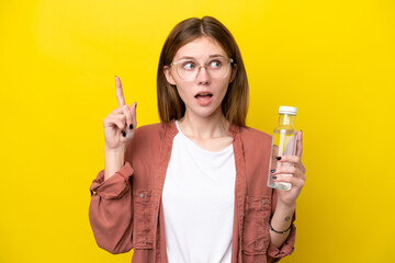 Young English woman with a bottle of water isolated on yellow background thinking an idea pointing...