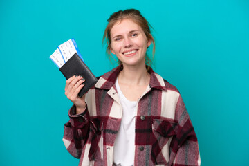 Young English woman isolated on blue background happy in vacation with passport and plane tickets