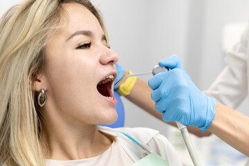 female dentist using water and air syringe tool, process of treatment in dental clinic