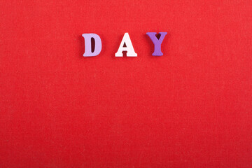 DAY word on red background composed from colorful abc alphabet block wooden letters, copy space for ad text. Learning english concept.