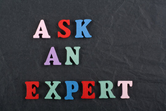 ASK AN EXPERT word on black board background composed from colorful abc alphabet block wooden letters, copy space for ad text. Learning english concept.