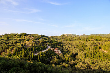 View in the evening under a blue sky over the hills and the forest near Paleokastrtitsa on the...