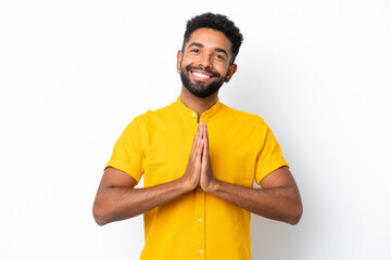 Young Brazilian man isolated on white background keeps palm together. Person asks for something