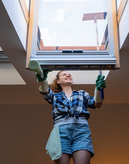 Woman cleaning roof light window at home using squeegee.