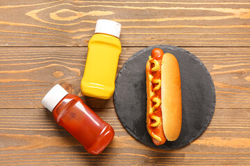 board with tasty hot dog, ketchup and mustard on wooden background