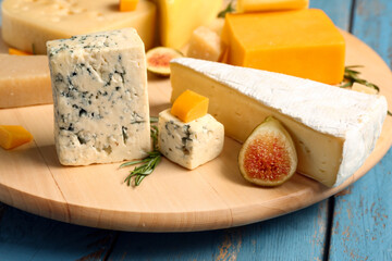 Board with tasty cheese on blue wooden background