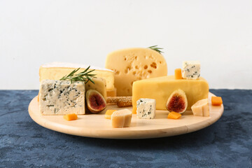 Wooden board with tasty cheese on table against white background