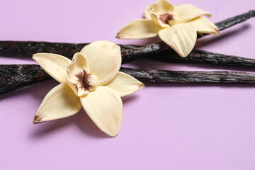 Aromatic vanilla sticks and flowers on lilac background