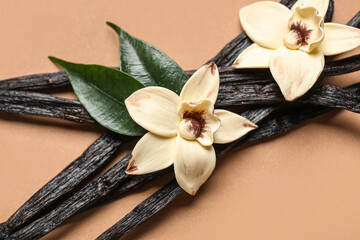Aromatic vanilla sticks and flowers on brown background