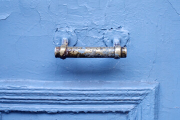 Old brass door handle on a blue painted door close up