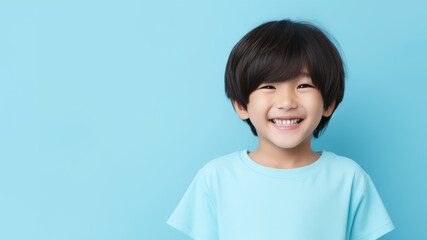 Asian child boy, bowl-cut black hair, pale blue studio - obrazy, fototapety, plakaty