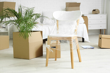 Wrapped chair with moving boxes in bedroom