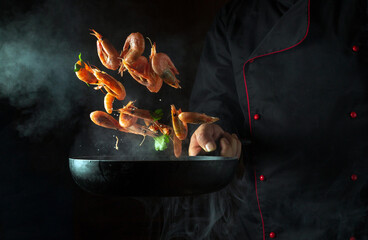 The chef cooks shrimp in a hot pan with steam. The concept of cooking seafood or healthy vegetarian...