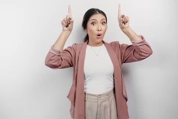 Foto op Canvas Shocked Asian woman employee wearing cardigan pointing at the copy space on top of her, isolated by white background © Reezky