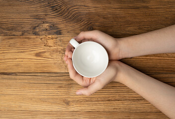 Hand Holds Cup, Empty White Cup in Hands, Coffee Mug, Teacup Mockup, Cup in Arms on Wooden Table