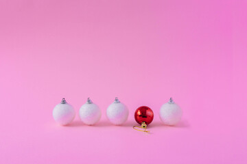 Creative layout made with a white Christmas bauble and a red disco ball against a pink pastel background. Minimal holiday decoration.