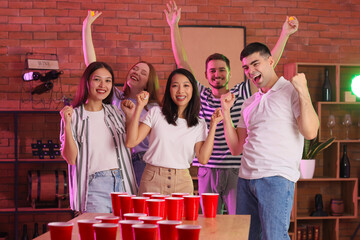 Group of young friends playing beer pong at party