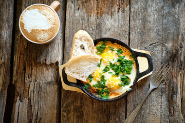 Fried egg with herbs and bread. Wooden background, top view.